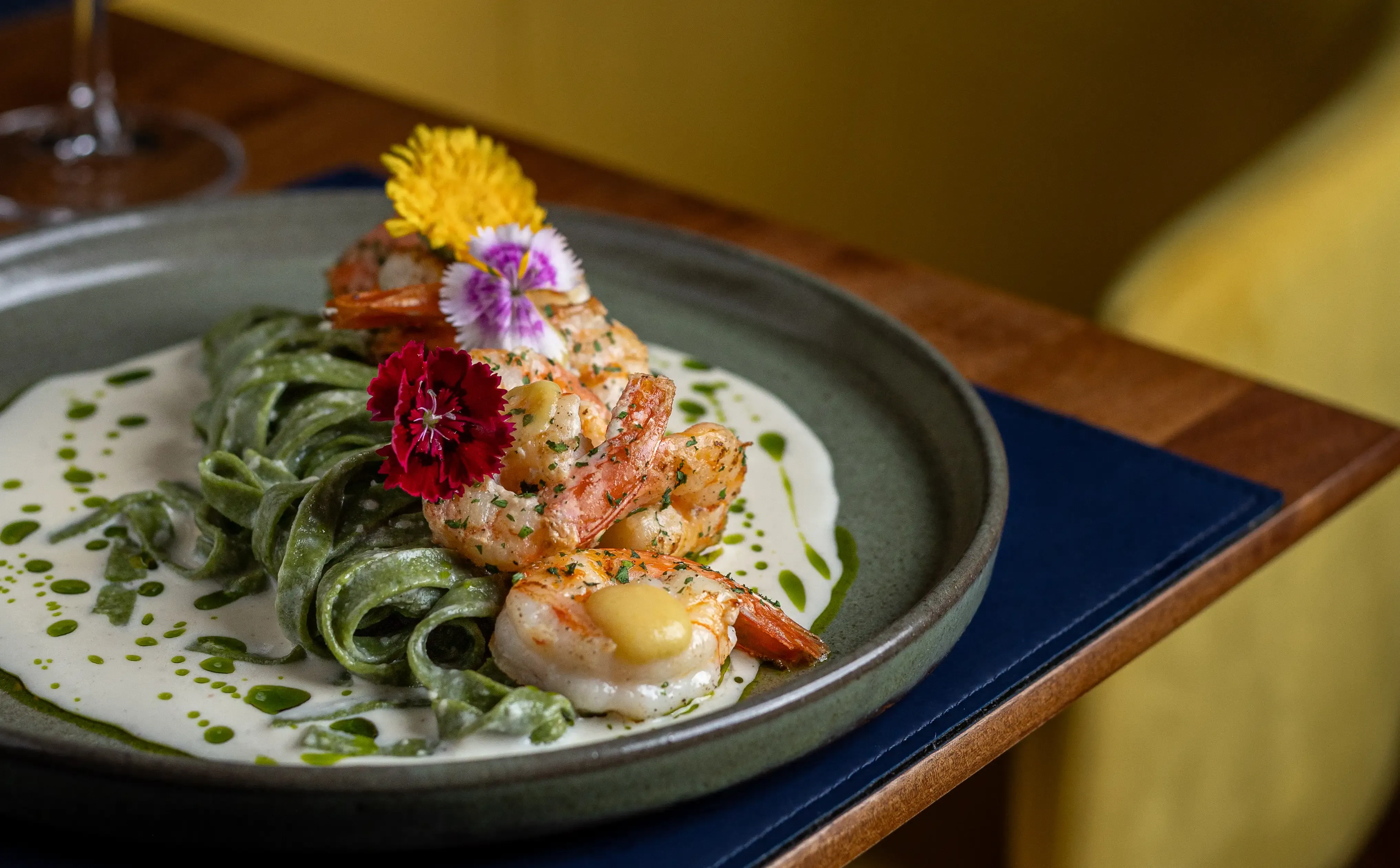 prato de macarrão com camarão e flores sob a mesa