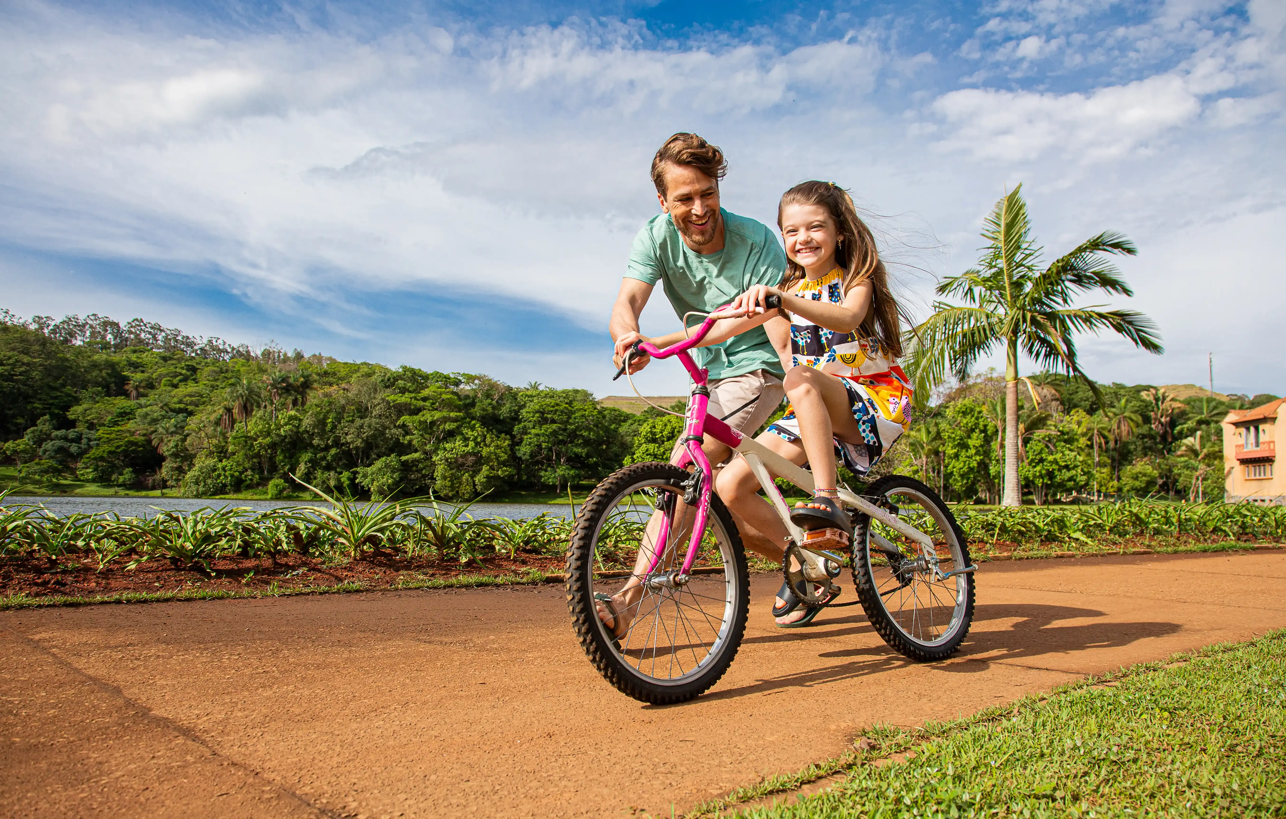 pai ensinando filha a andar de bicicleta