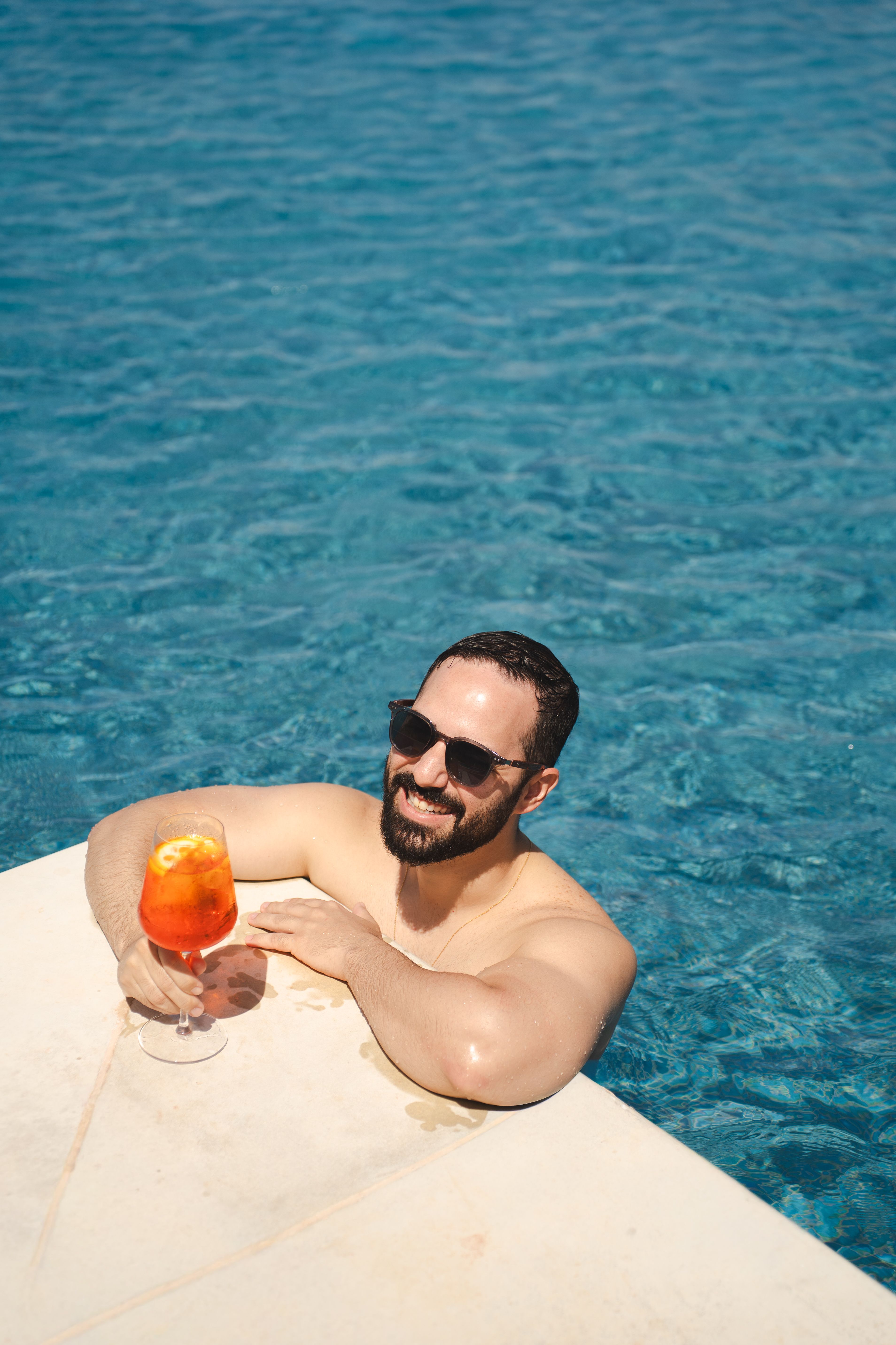 homem com drink na piscina