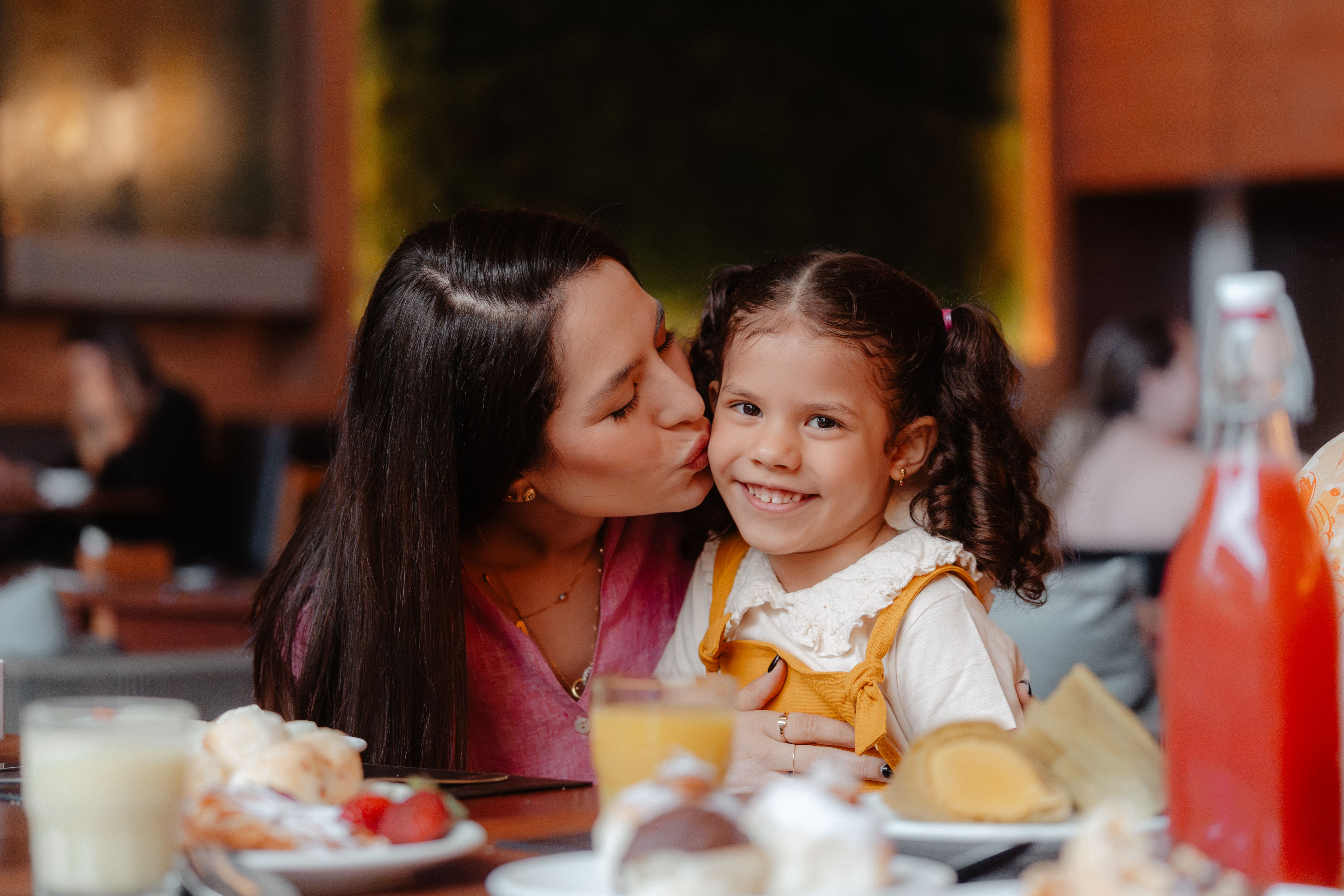 mãe dando beijo na bochecha da filha
